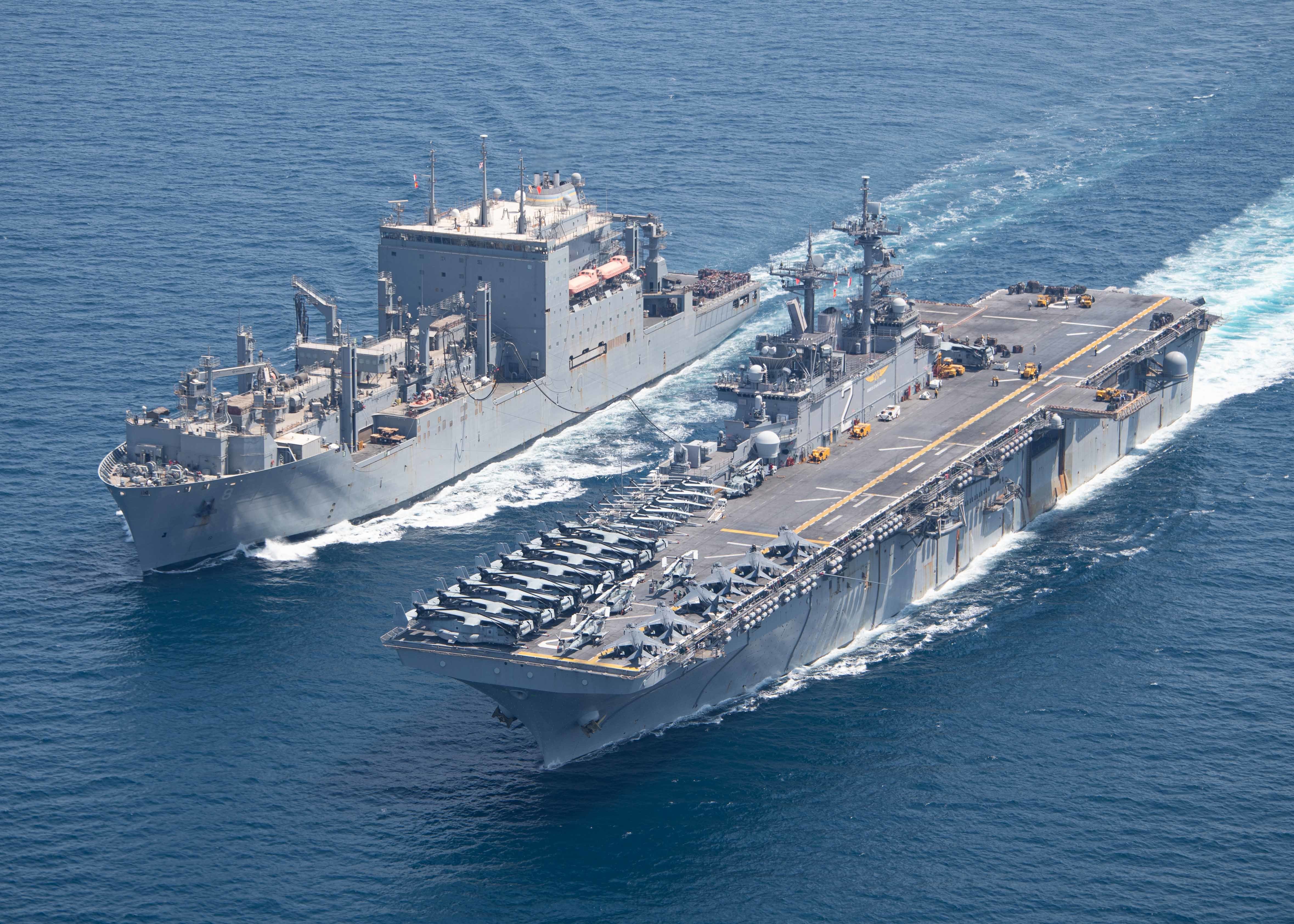 The dry cargo and ammunition ship USNS Wally Schirra (T-AKE 8), left, conducts a replenishment-at-sea with the amphibious assault ship USS Essex (LHD 2), right, Sept. 18, 2021.