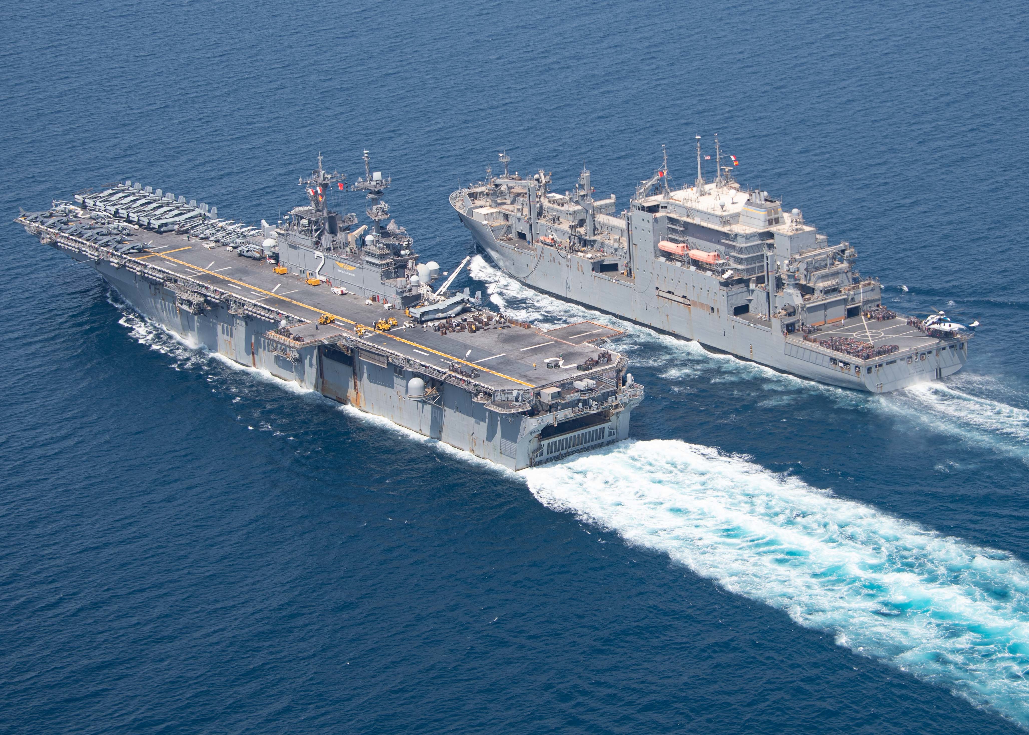 The dry cargo and ammunition ship USNS Wally Schirra (T-AKE 8), right, conducts a replenishment-at-sea (RAS) with the amphibious assault ship USS Essex (LHD 2), left, Sept. 18, 2021.