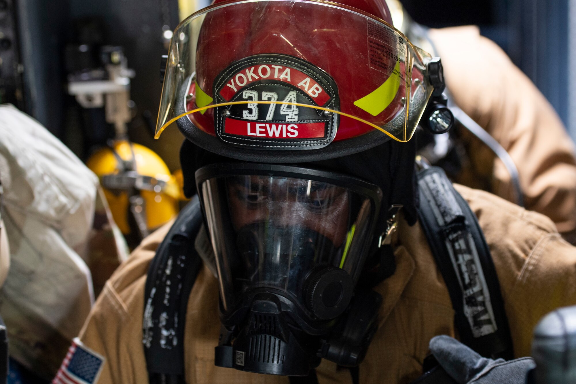Close-up of a firefighter wearing a red helmet and respirator mask