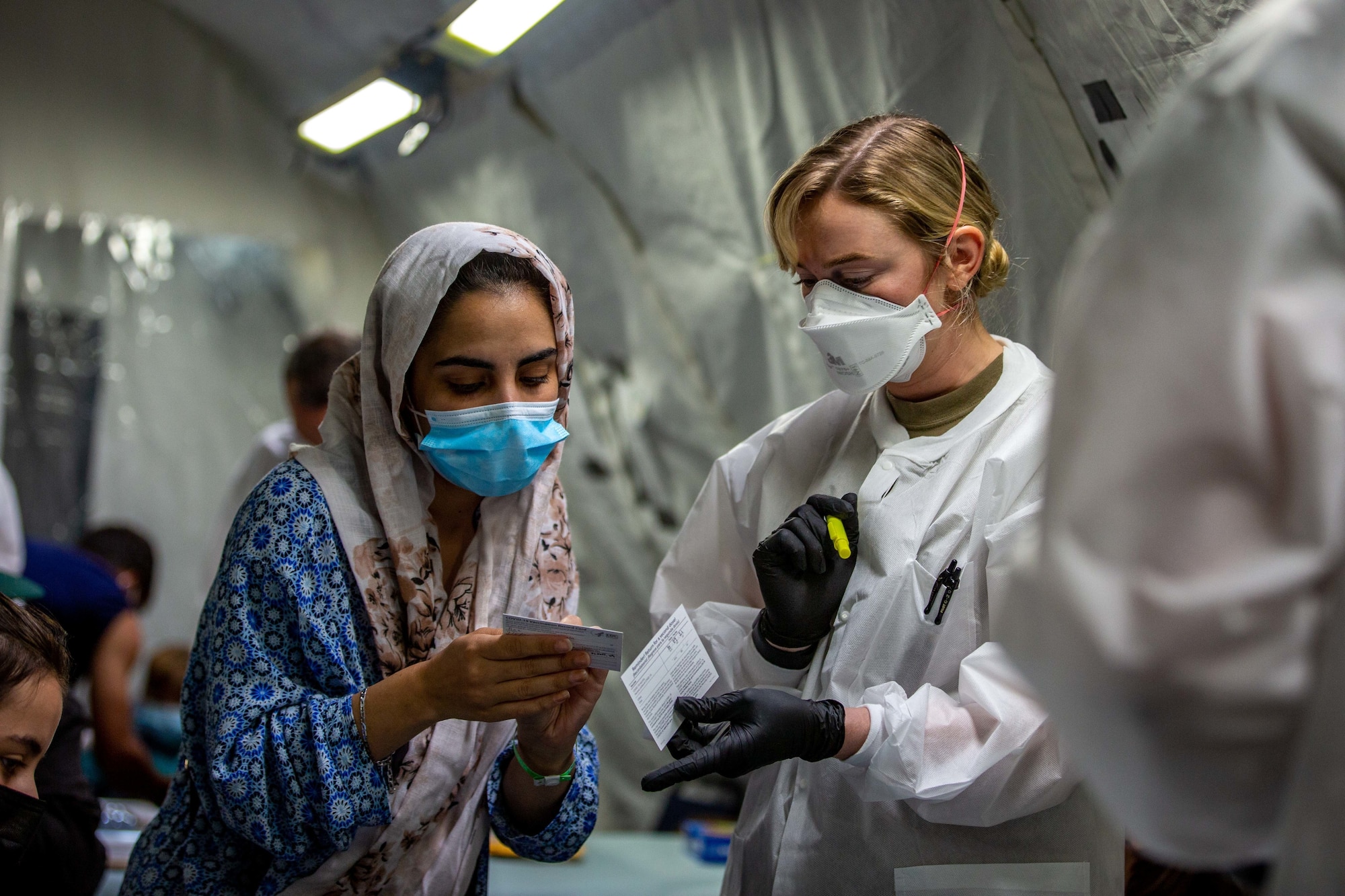 U.S. Air Force 1st Lt. Annie Darroch, a registered nurse (RN) with the 96th Medical Group, provides vaccinations to Afghan individuals on Fort Pickett, Virginia, Sept. 18, 2021.