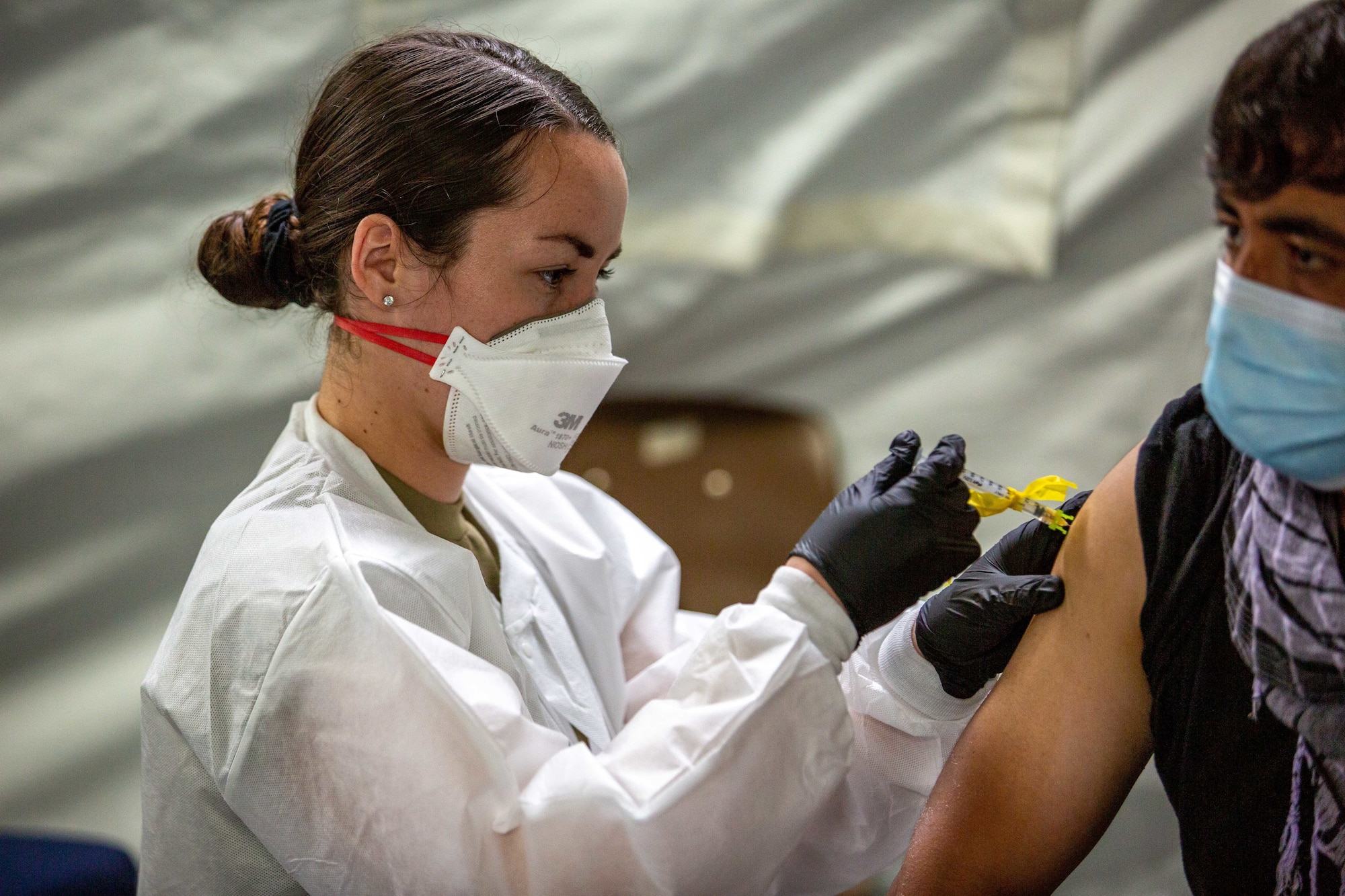 U.S. Air Force Senior Airman Julia Evans, a medic with the 96th Medical Group, provides a Pfizer COVID vaccination to an Afghan individual on Fort Pickett, Virginia, Sept. 18, 2021.