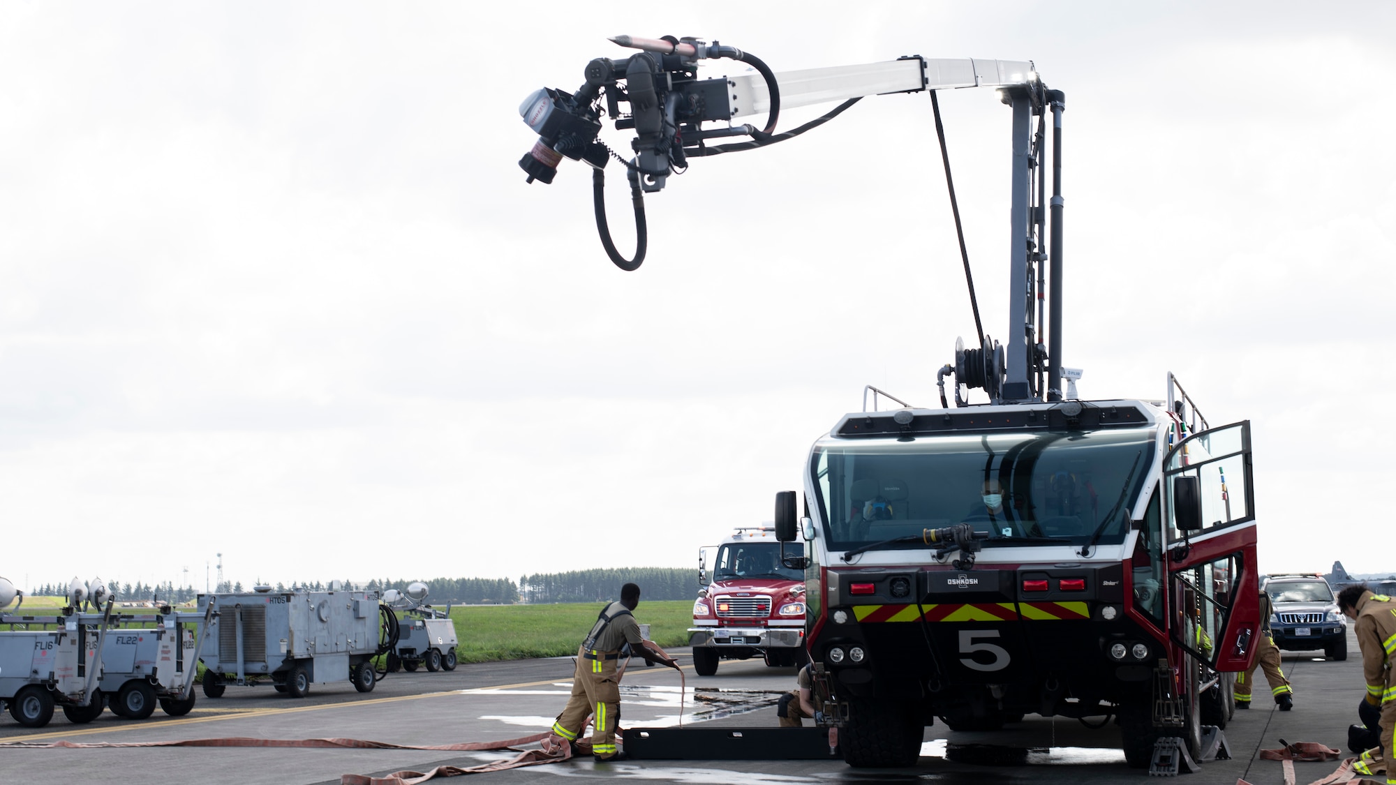 A red fire truck extends a large spike on the end of a overhead arm