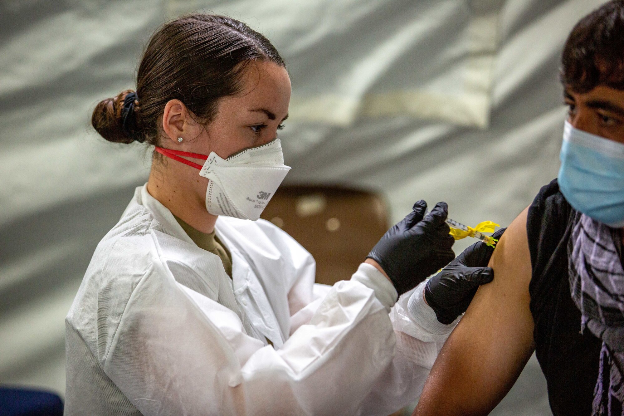 U.S. Air Force Senior Airman Julia Evans, a medic with the 96th Medical Group, provides a Pfizer COVID vaccination to an Afghan individual on Fort Pickett, Virginia, Sept. 18, 2021.