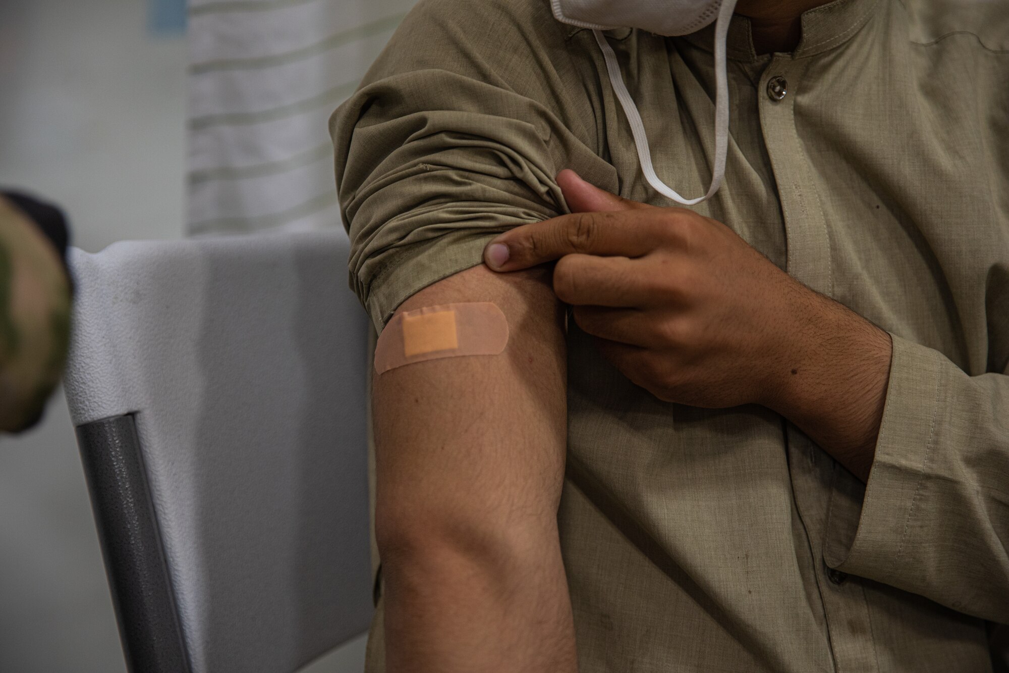 An Airman attached to Task Force-Holloman administers a vaccination to an Afghan evacuee in support of Operation Allies Welcome on Holloman Air Force Base, New Mexico, Sept. 20, 2021. The Department of Defense, through U.S. Northern Command, and in support of the Department of State and Department of Homeland Security, is providing transportation, temporary housing, medical screening, and general support for at least 50,000 Afghan evacuees at suitable facilities, in permanent or temporary structures, as quickly as possible. This initiative provides Afghan evacuees essential support at secure locations outside Afghanistan. (U.S. Army photo by Pfc. Anthony Sanchez)