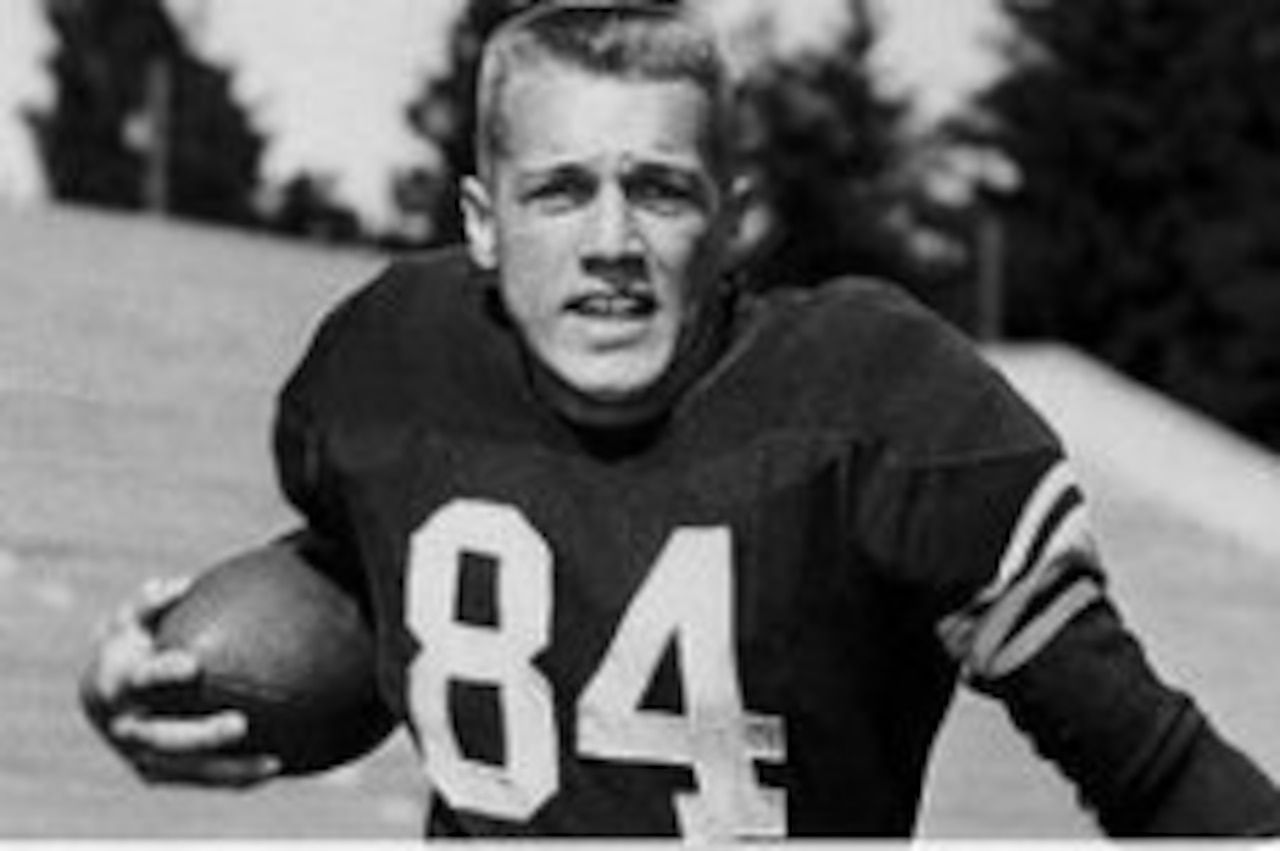 Football player poses holding football.