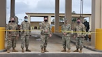five military members in uniform cut a ribbon