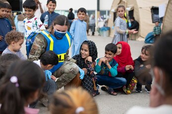 U.S. Air Force Senior Airman Meghan Ballard, 423rd Security Forces pass and registration supervisor assigned to Royal Air Force Alconbury, England, plays a game with children during Operation Allies Refuge at Ramstein Air Base, Germany, Aug. 31, 2021. Volunteers work around the clock to support evacuees during their time at Ramstein. Ramstein Air Base transformed into U.S. European Command’s primary evacuation hub, supporting one of the largest, most complex humanitarian airlift operations in history. (U.S. Air Force photo by Senior Airman Jennifer Zima)