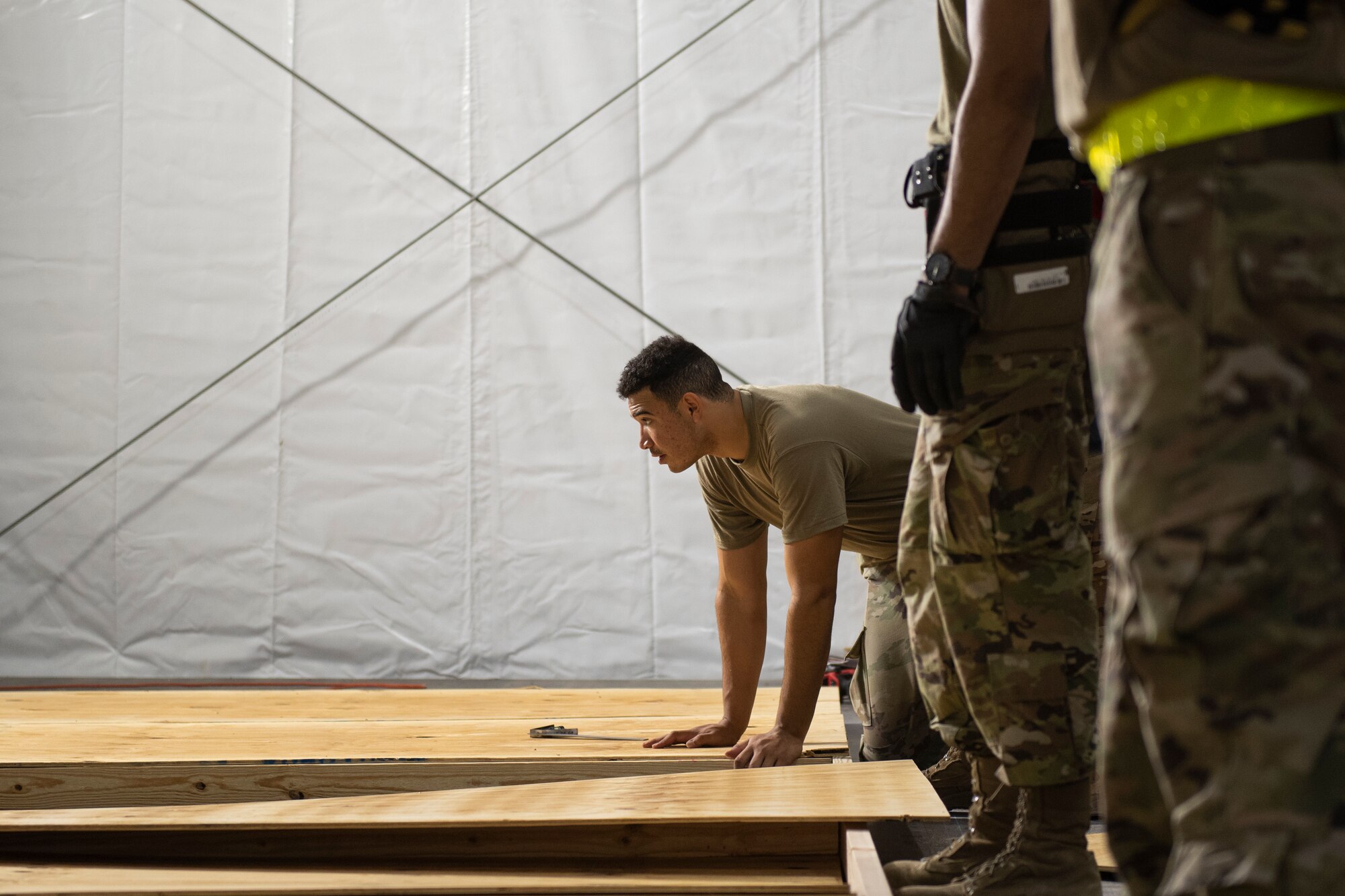 An Airman from Task Force-Holloman lines up wood to build partitions for Afghan evacuee living quarters on Holloman Air Force Base, New Mexico, Sept. 4, 2021. The Department of Defense, through U.S. Northern Command, and in support of the Department of State and Department of Homeland Security, is providing transportation, temporary housing, medical screening, and general support for at least 50,000 Afghan evacuees at suitable facilities, in permanent or temporary structures, as quickly as possible. This initiative provides Afghan evacuees essential support at secure locations outside Afghanistan. (U.S. Air Force photo by Staff Sgt. Kenneth Boyton)