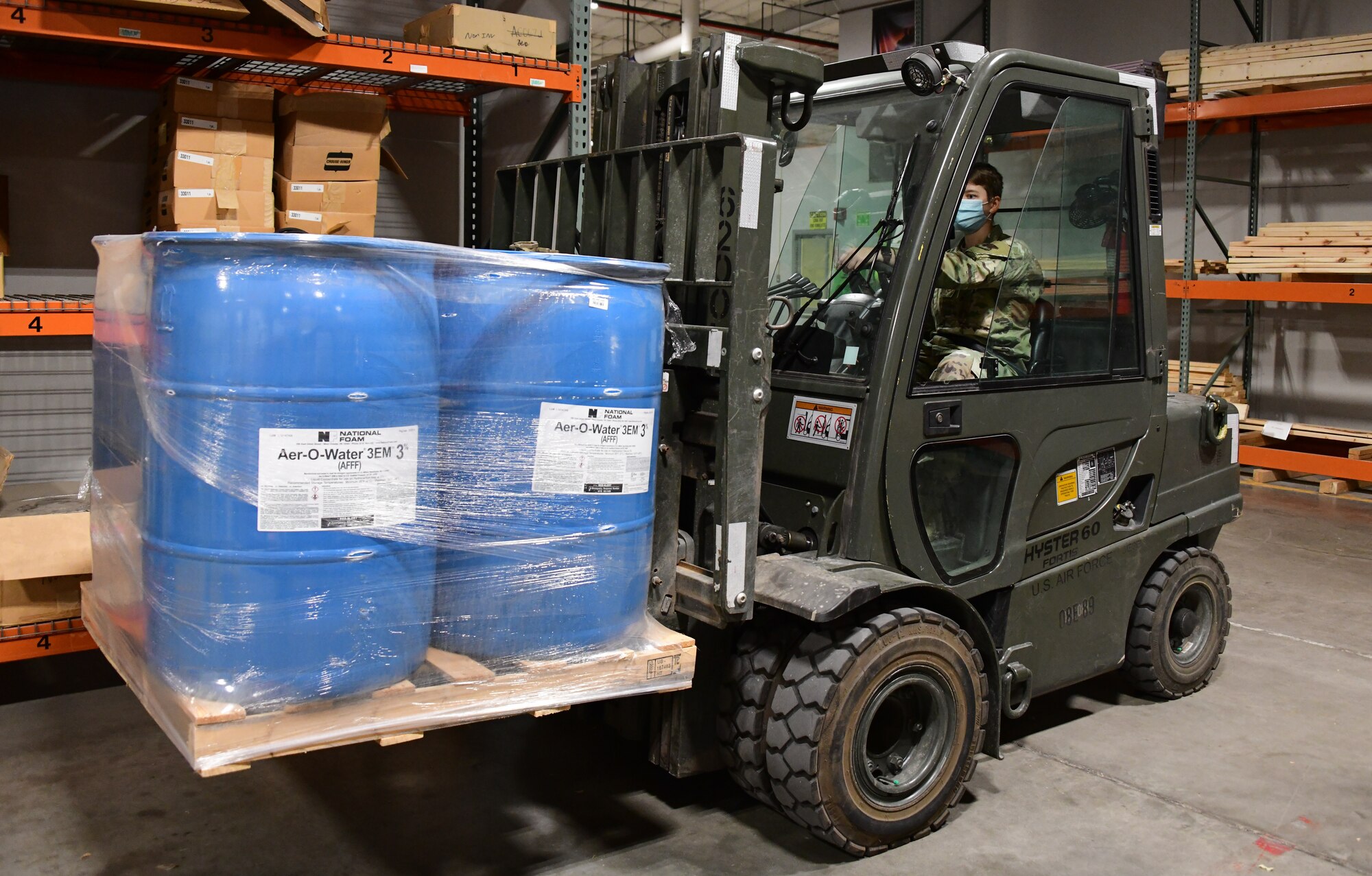 A1C Moskvichova sits in a forklift that is holding a pallet of large barrels labeled "Aer-O-Water"