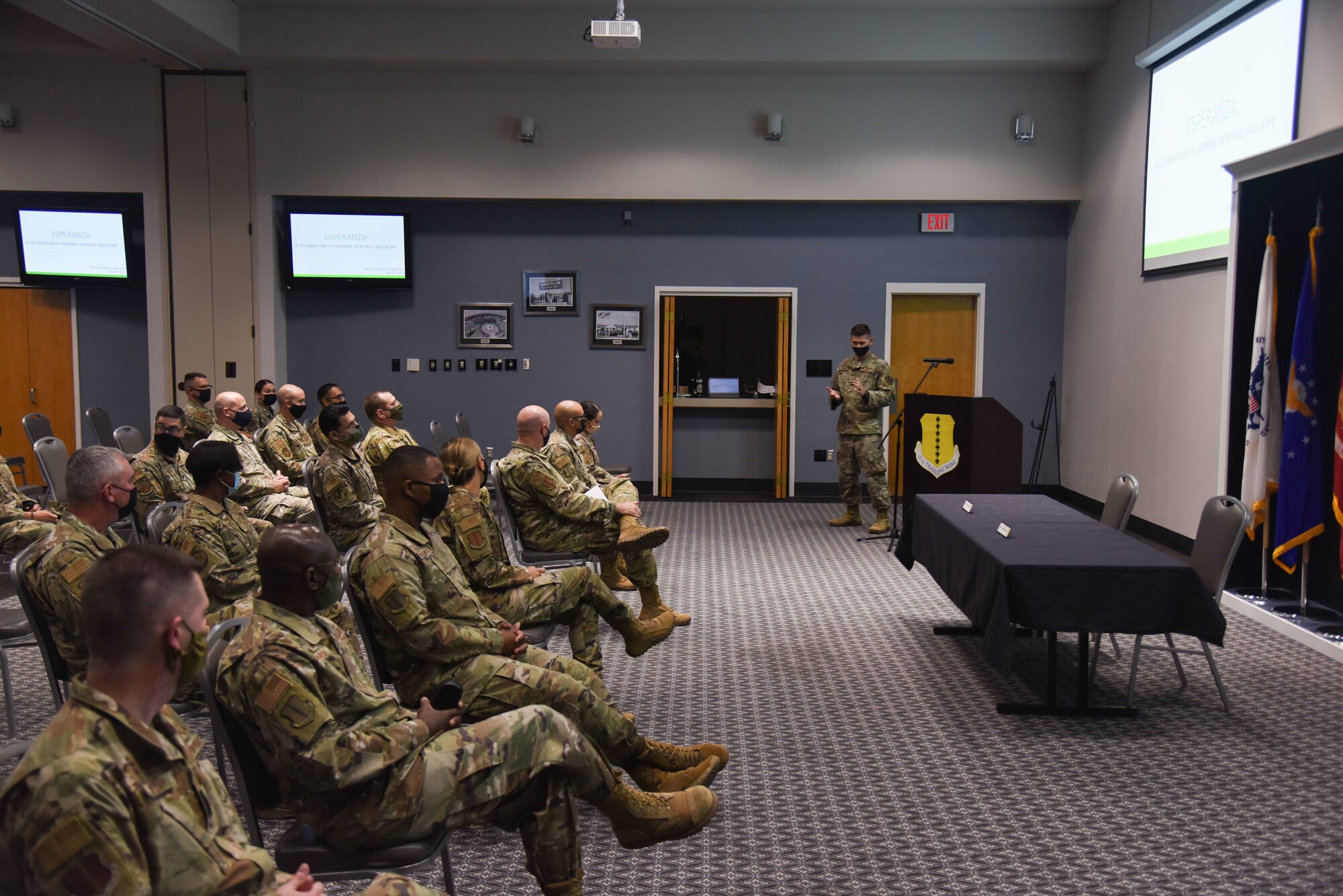 Air Force members sit and watch a photo galley presentation during an event