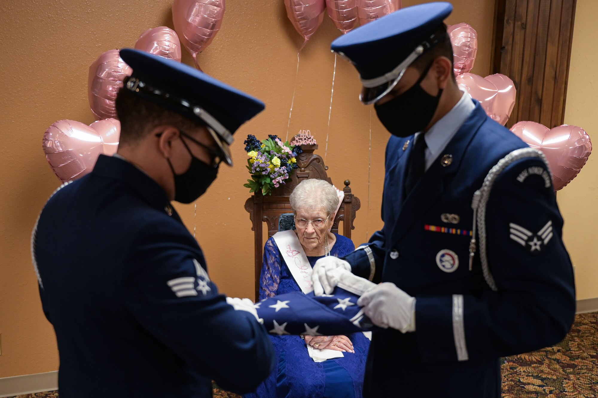 Senior Airman Gabriel Bryant, left, and Senior Airman Christian Luna, 22nd Force Support Squadron honor guardsmen, fold a flag for Fran Harris, former secretary for the Base Supply commander at Ellsworth Air Force Base, S.D., during her100th birthday celebration in Rapid City, S.D., Sept. 11, 2021.