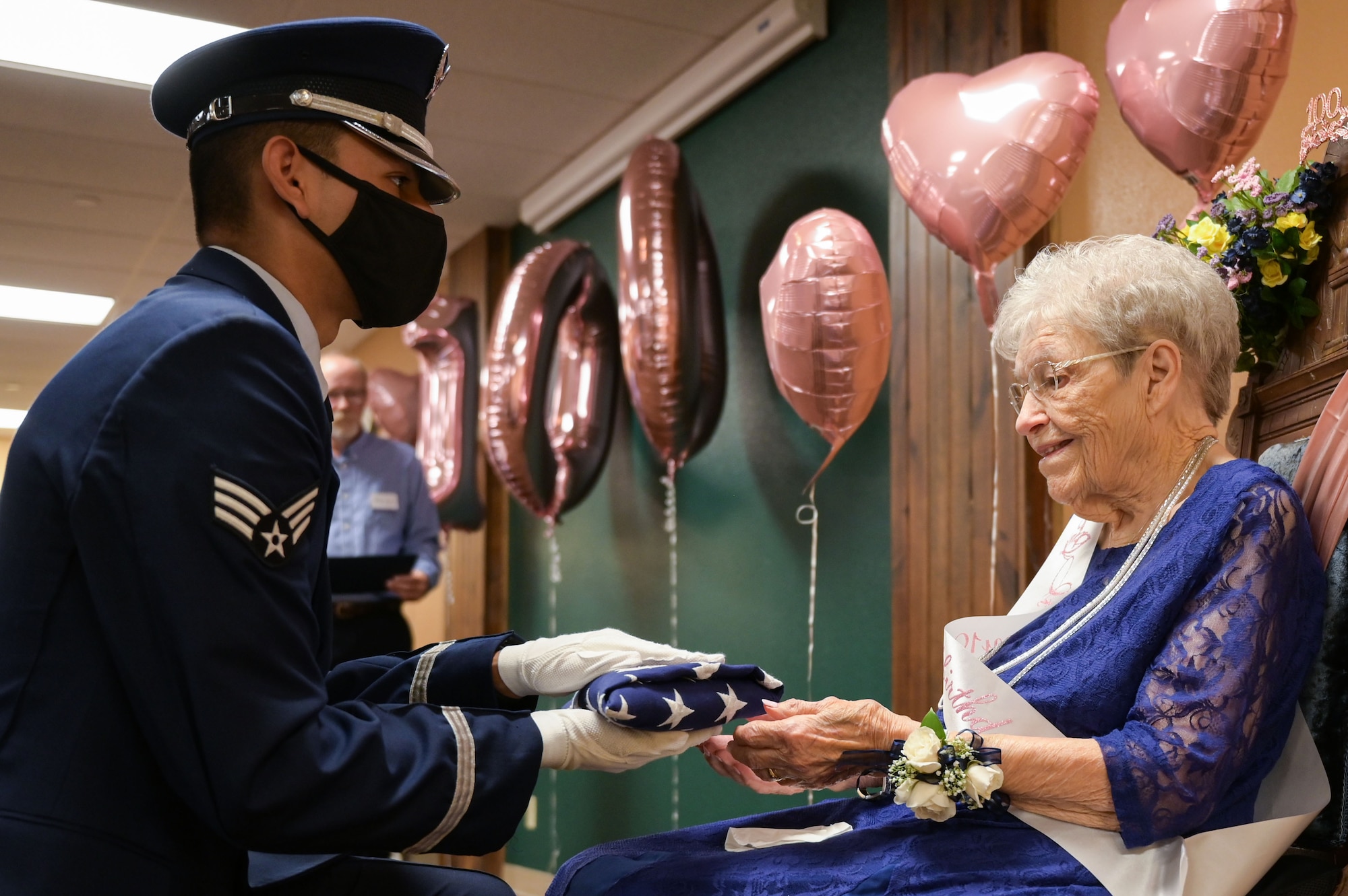 Senior Airman Christian Luna, 22nd Force Support Squadron honor guardsman, presents a flag to Fran Harris, former secretary for the Base Supply commander at Ellsworth Air Force Base, S.D., during her birthday in Rapid City, S.D., Sept. 11, 2021
