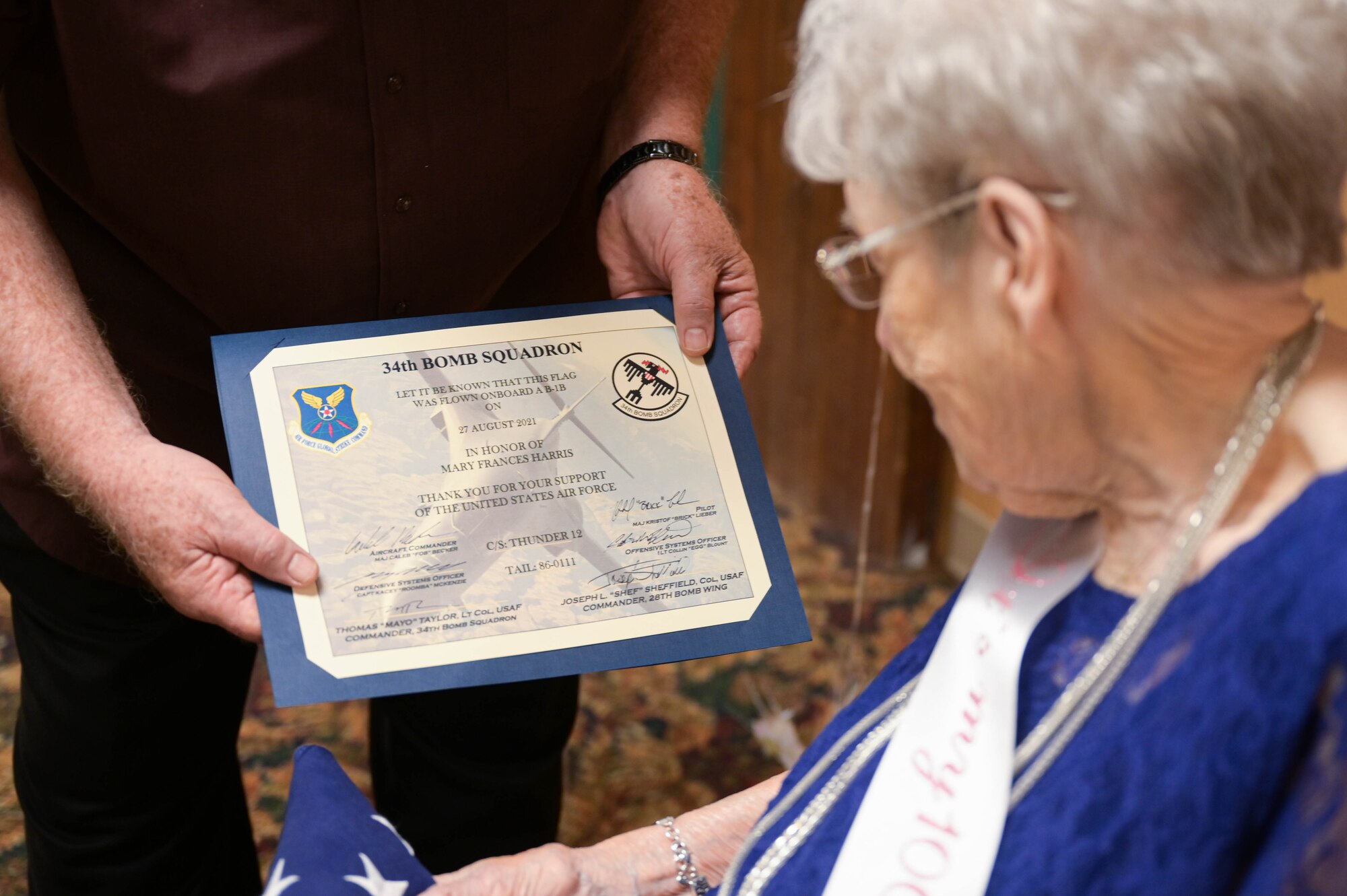 Fran Harris, former secretary for the Base Supply commander at Ellsworth Air Force Base, S.D., is presented a certificate of authenticity stating the flag she was given was flown on a B-1B Lancer, during her 100th birthday party in Rapid City, S.D., Sept. 11, 2021.