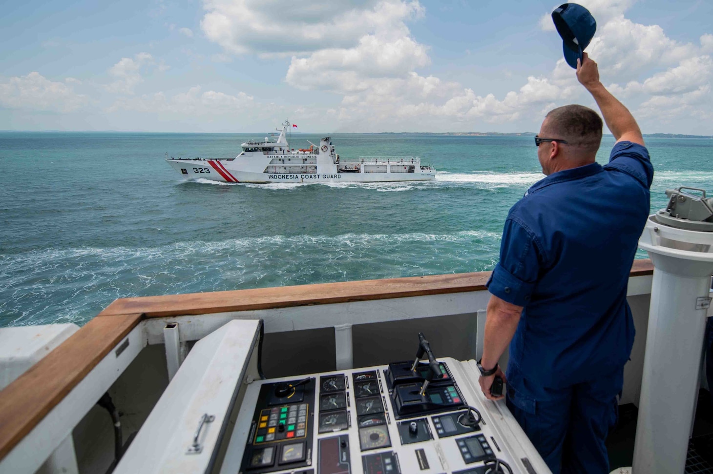 Capt. Blake Novak, commanding officer of Coast Guard Cutter Munro, waves goodbye after an exercise at sea with the Indonesian Coast Guard in the Singapore Strait, September 20, 2021. The United States Coast Guard is proud to operate with our Pacific counterparts, and together we are dedicated to enhancing capabilities, strengthening maritime governance and security while promoting a rules-based international order. (U.S. Coast Guard photo by Seaman Ian Gray)