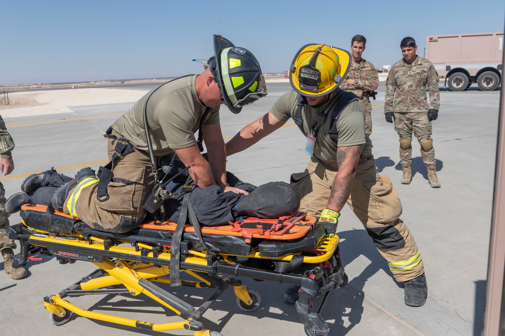 U.S. Airmen with the 332nd Expeditionary Medical Group and the 332nd Expeditionary Civil Engineering Squadron participate in a rescue exercise for a simulated aircraft fire