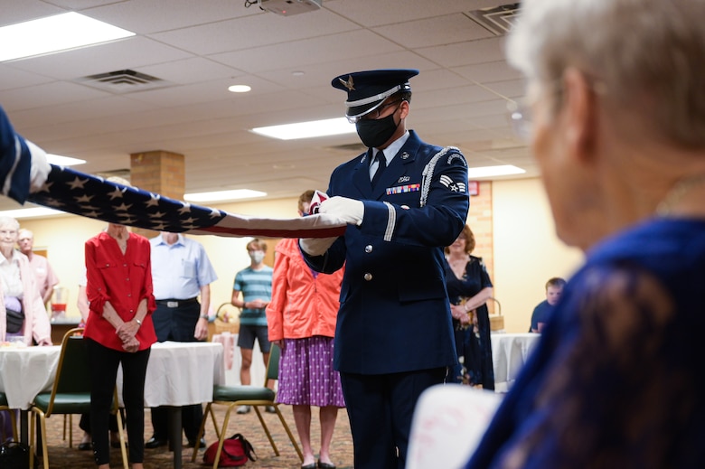 Senior Airman Gabriel Bryant, 22nd Force Support Squadron honor guardsman, folds a flag in honor of Fran Harris, former secretary for the Base Supply commander at Ellsworth Air Force Base, S.D., during her 100th birthday party in Rapid City, S.D., Sept. 11, 2021.