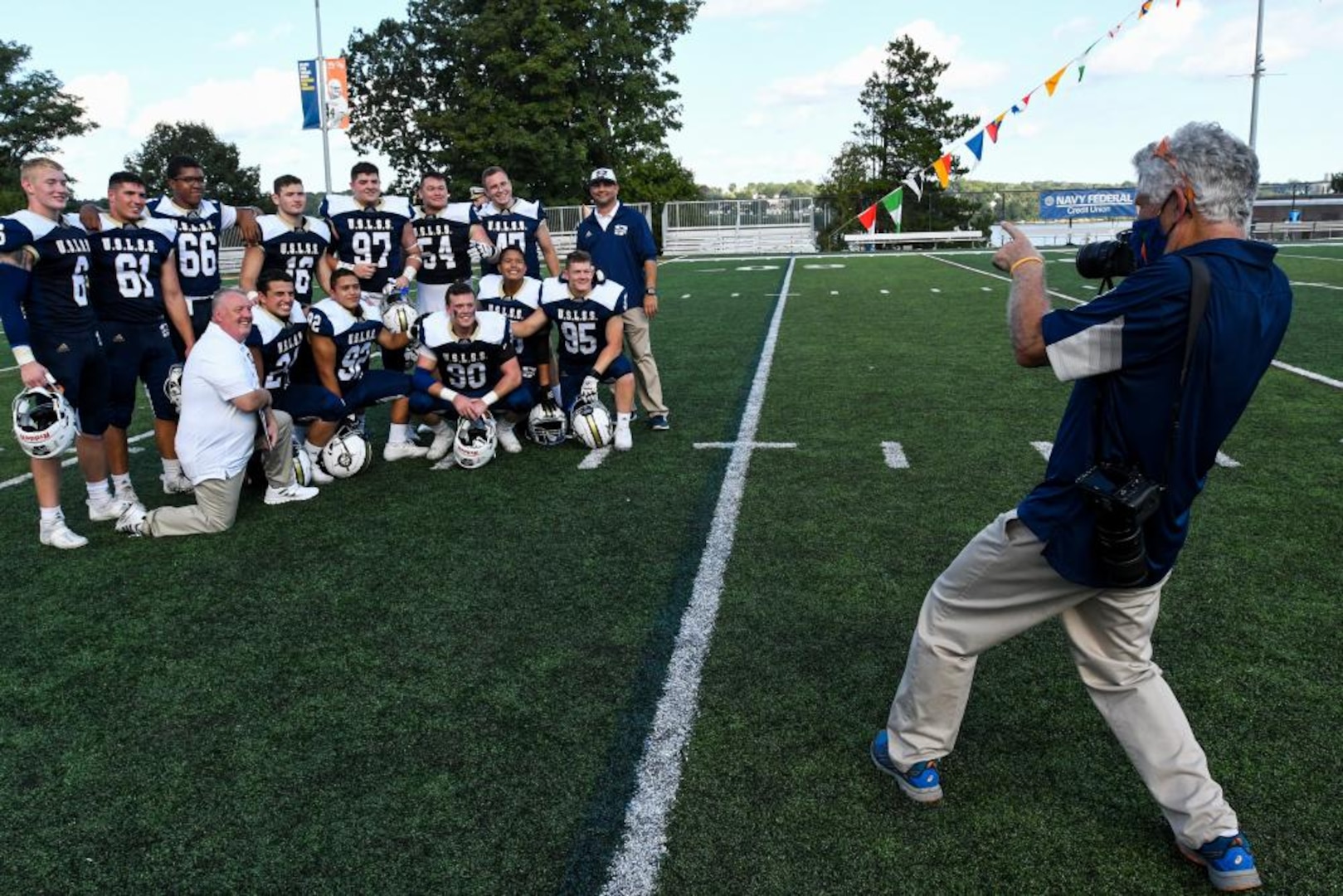 Paul Duddy, freelance photographer at the U.S. Coast Guard Academy, photographs football players, Sept 18, 2021. Duddy has supported the Academy with his photography for over 16 years. (U.S. Coast Guard courtesy photo by Brad Clift)