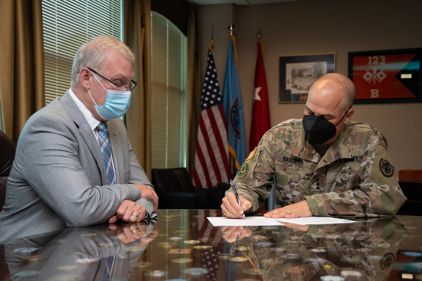 Photo of two men at a table signing a document.