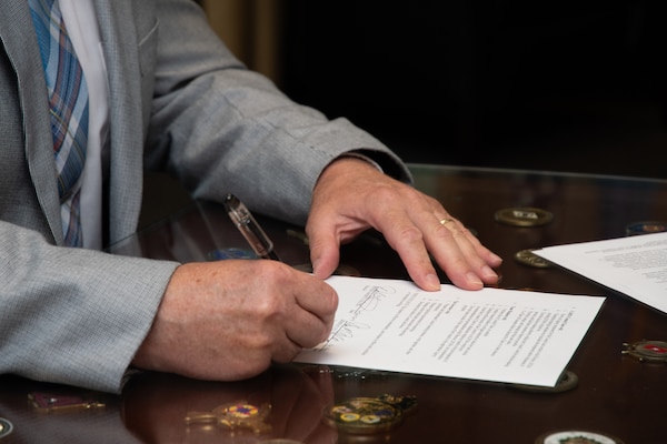 Close-up of a man's hand as he signs a document.