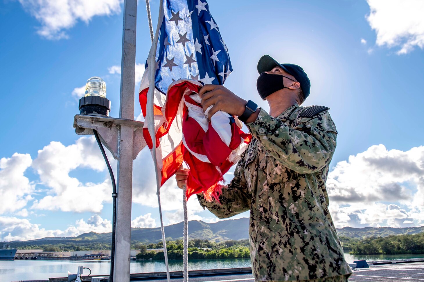 Culinary Specialist Seaman Apprentice Jeremy Reynolds, from Atlanta, hoists the ensign during morning colors aboard the Independence-variant littoral combat ship USS Charleston (LCS 18).