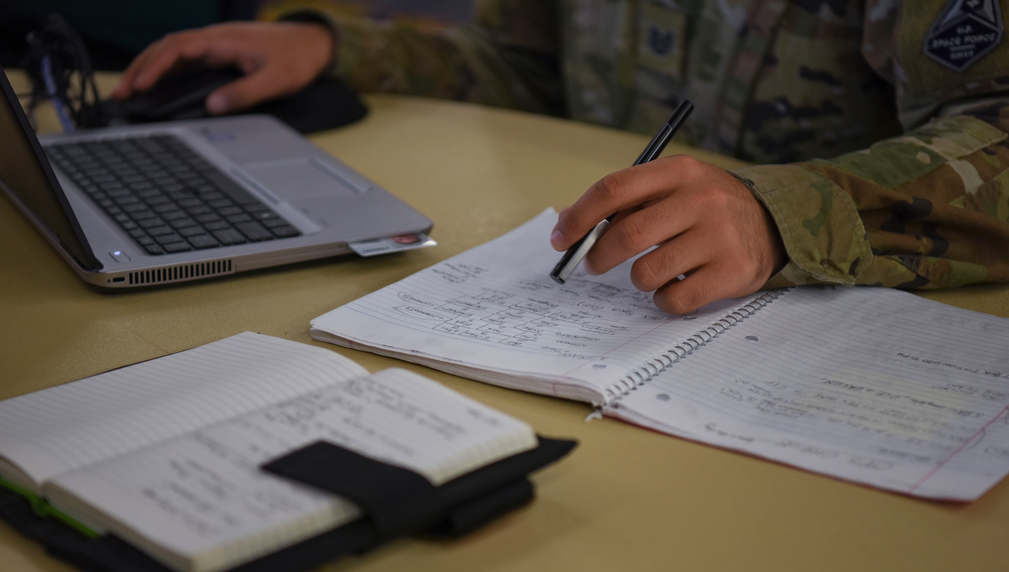 A Guardian works on their bot's coding through writing and on their computer.