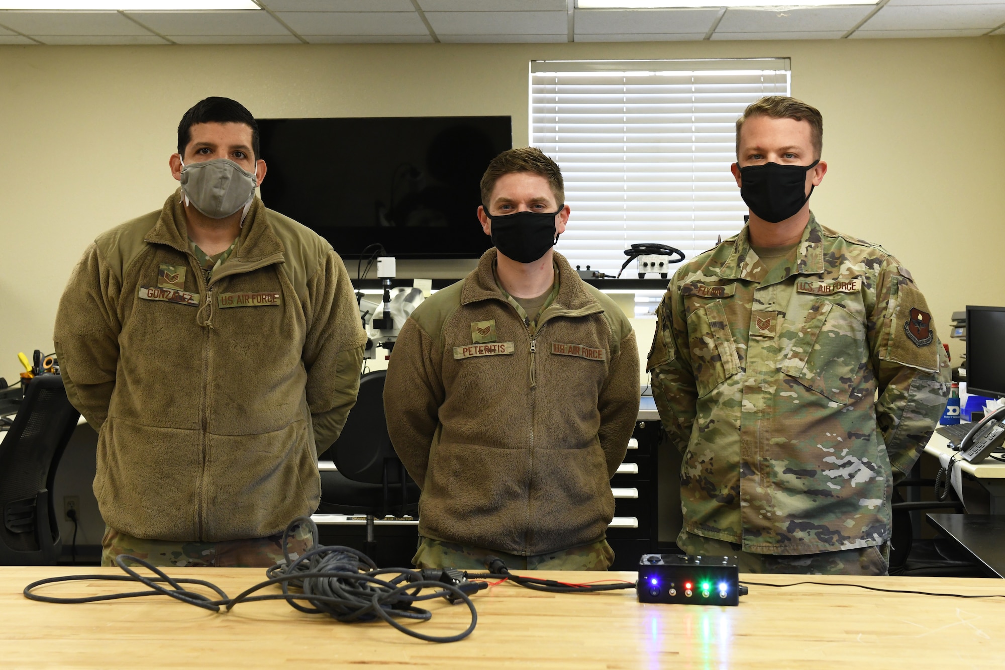 U.S. Air Force Tech. Sgt. Jonathan Gonzalez, left, and Staff Sgt. Gary Peteritis, center, both 56th Maintenance Group Air Force Repair and Enhancement Program technicians, stand with Tech. Sgt. Brady Flynn, right, 56th MXG Continuous Improvement and Innovation manager, to showcase the first prototype of the F-35A Lightning II communication cable rebuild and class tester box February 5, 2021, at Luke Air Force Base, Arizona. The development of the tester box has improved communication between pilots and maintainers on the flight line by allowing Airmen to rebuild F-35 communication cables at the unit level. This is one of many initiatives that advances the 56th MXG CII office’s mission to find errors, fix problems and empower the future of the 56th Fighter Wing. (U.S. Air Force photo by Tech. Sgt. Amber Carter)