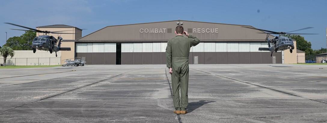 man saluting 2 helicopters