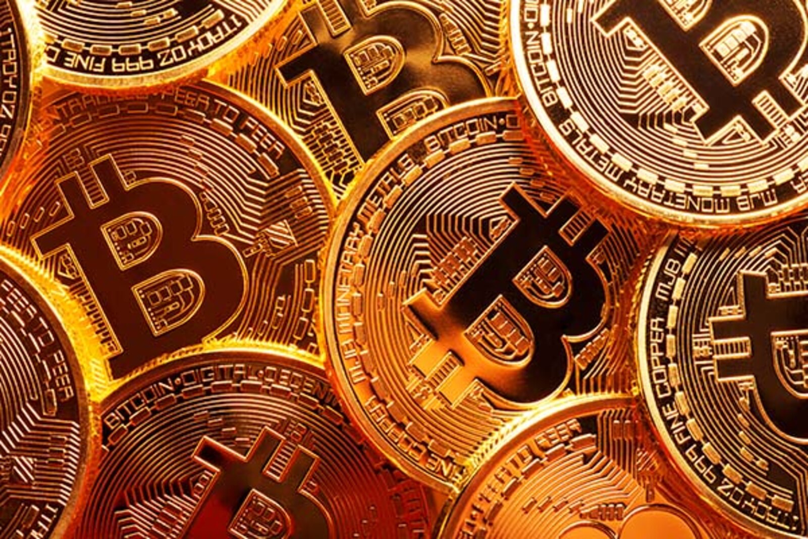 Close-up photo of several gold plated bitcoins together symbolizing the bitcoin market.