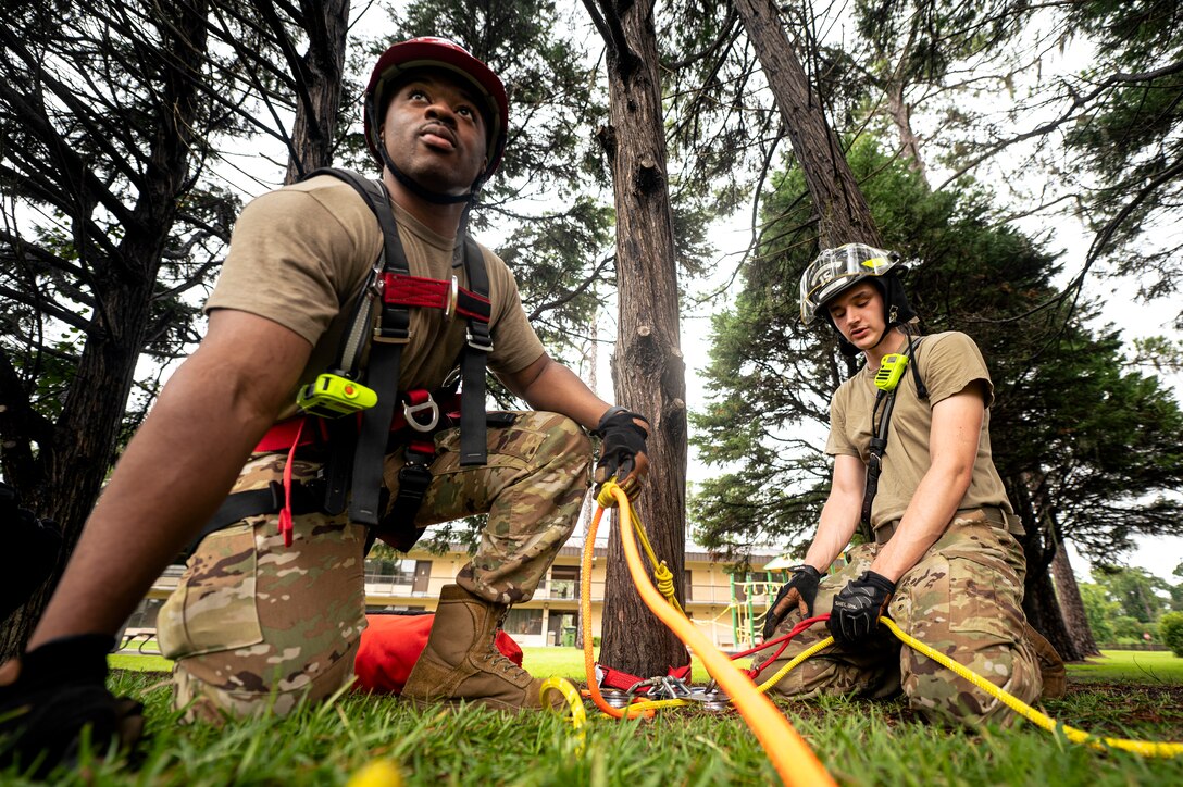 Photo of two firefighters kneeling in grass holding rope