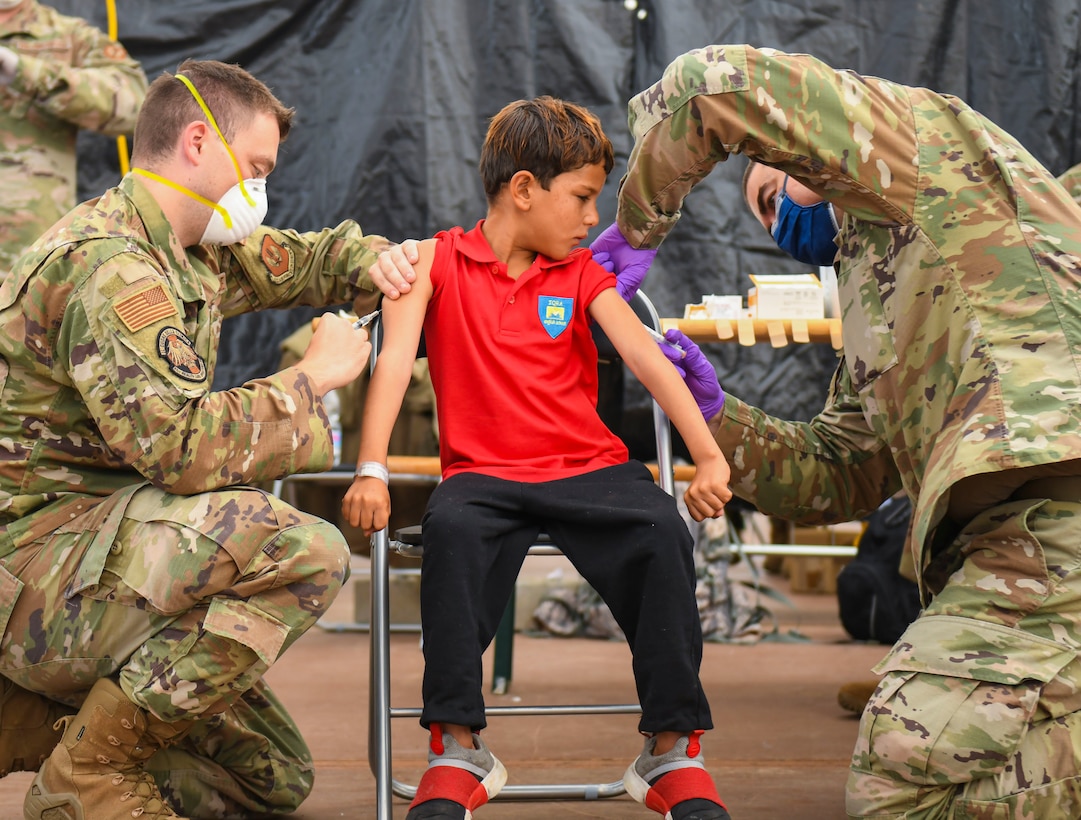 Medical reps administer vaccine to evacuee.
