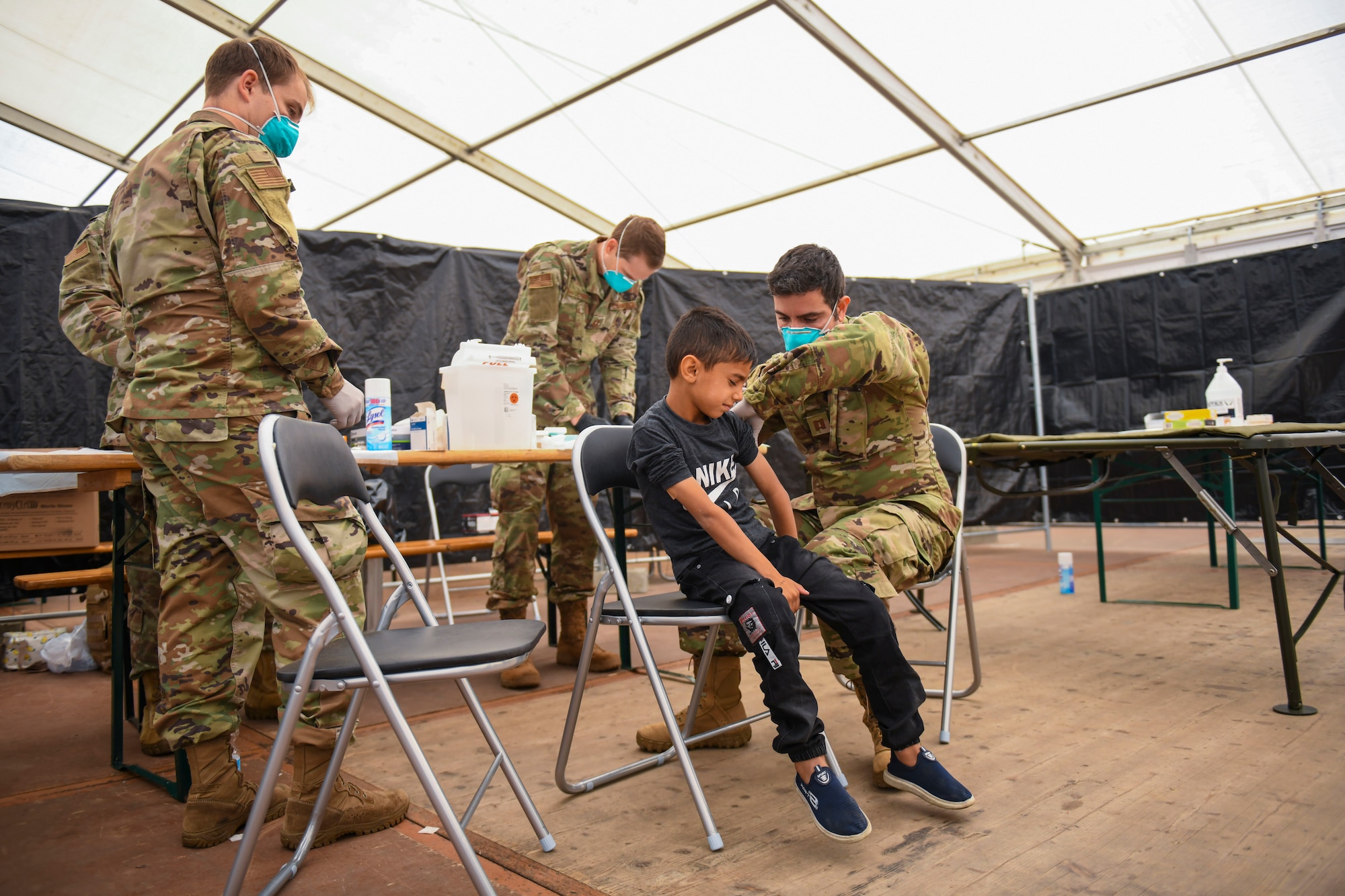 Airmen administer vaccine to evacuee.