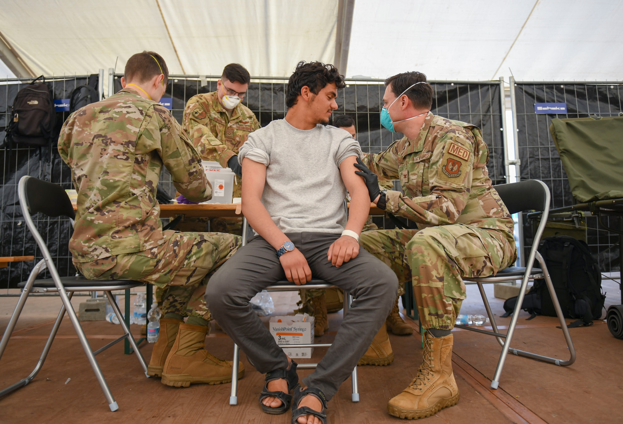 Airmen administer vaccine to evacuees.