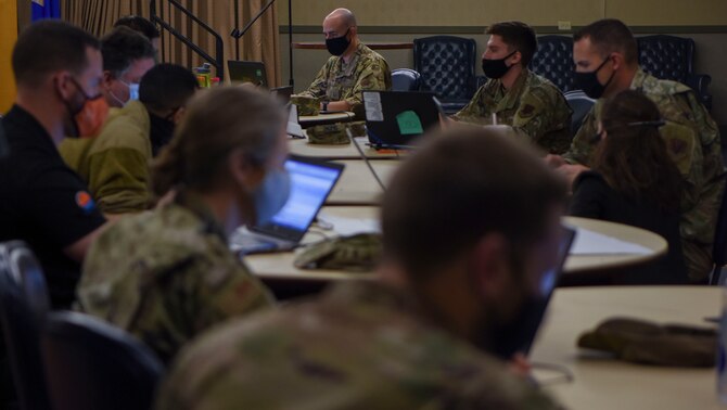 Airmen and Guardians watch as an airman presents their bot the the group.