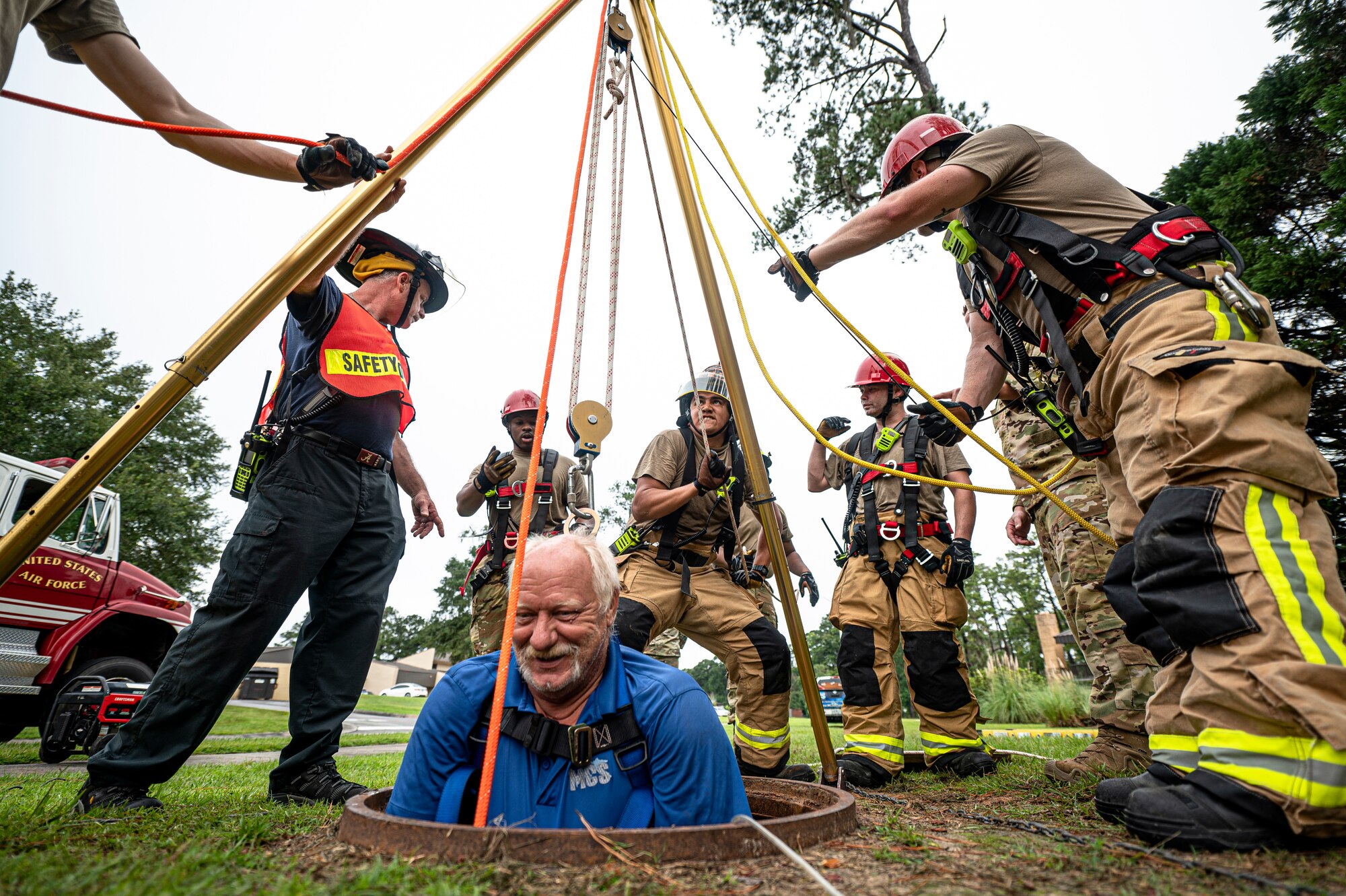 Photo of firefighters using a pulley system to raise an individual from a manhole