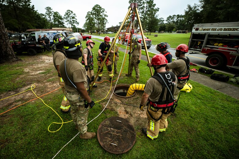 Photo of a group of firefighters standing around a manhole