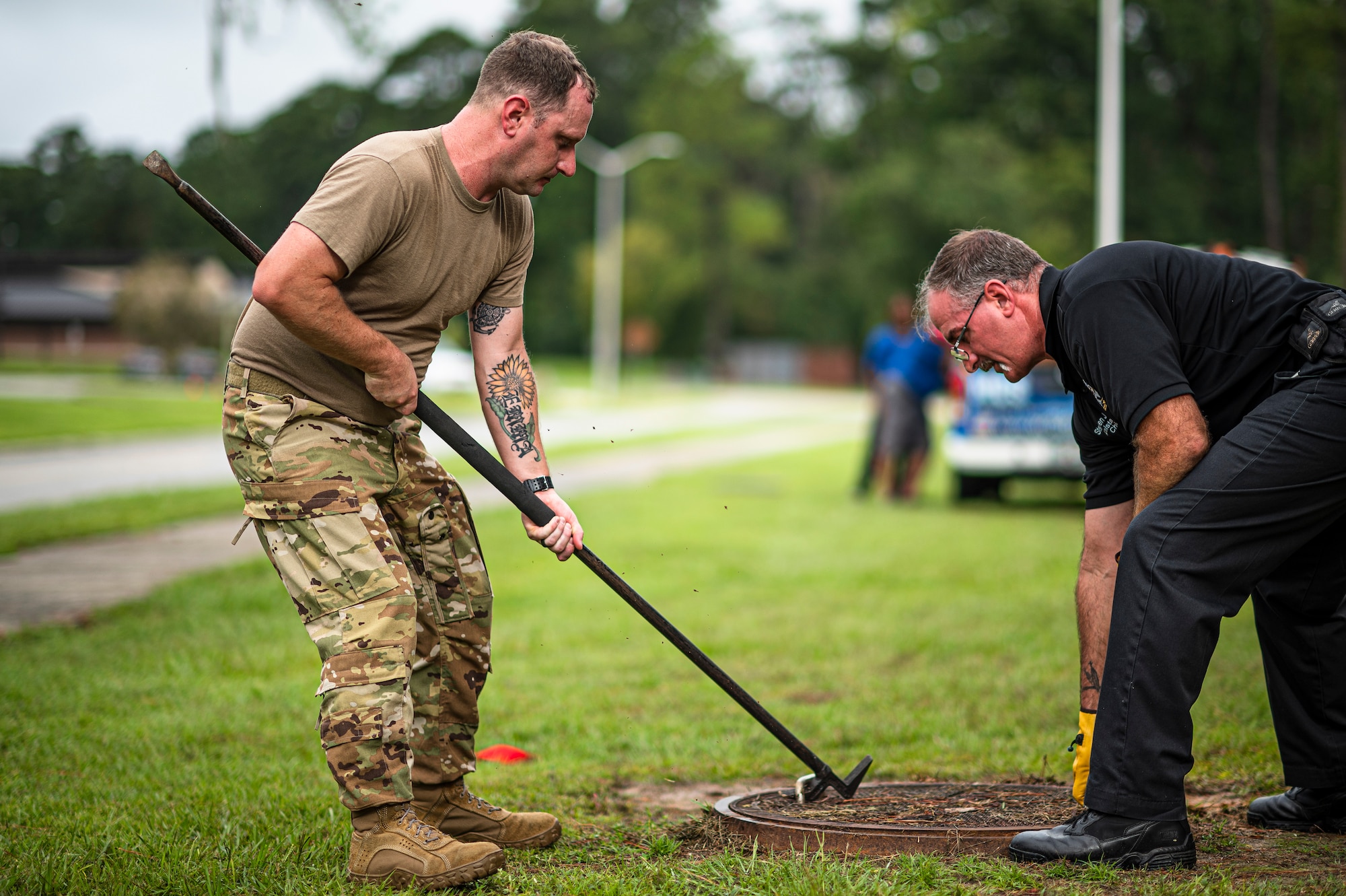 Photo of Airman using a tool to close a manhole