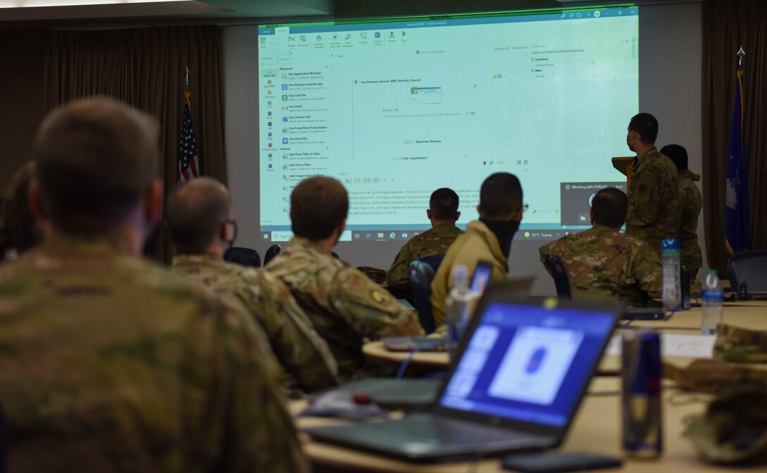 Airmen and Guardians watch as an airman presents their bot the the group.