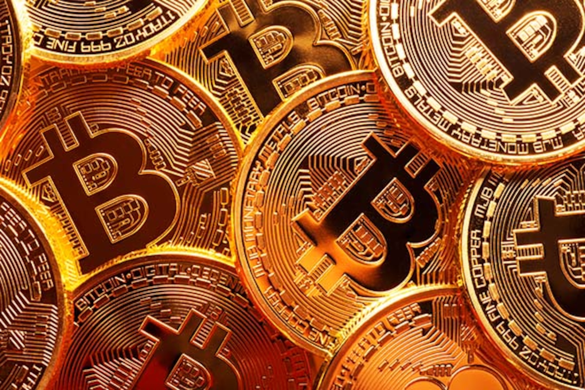 Close-up photo of several gold plated bitcoins together symbolizing the bitcoin market.
