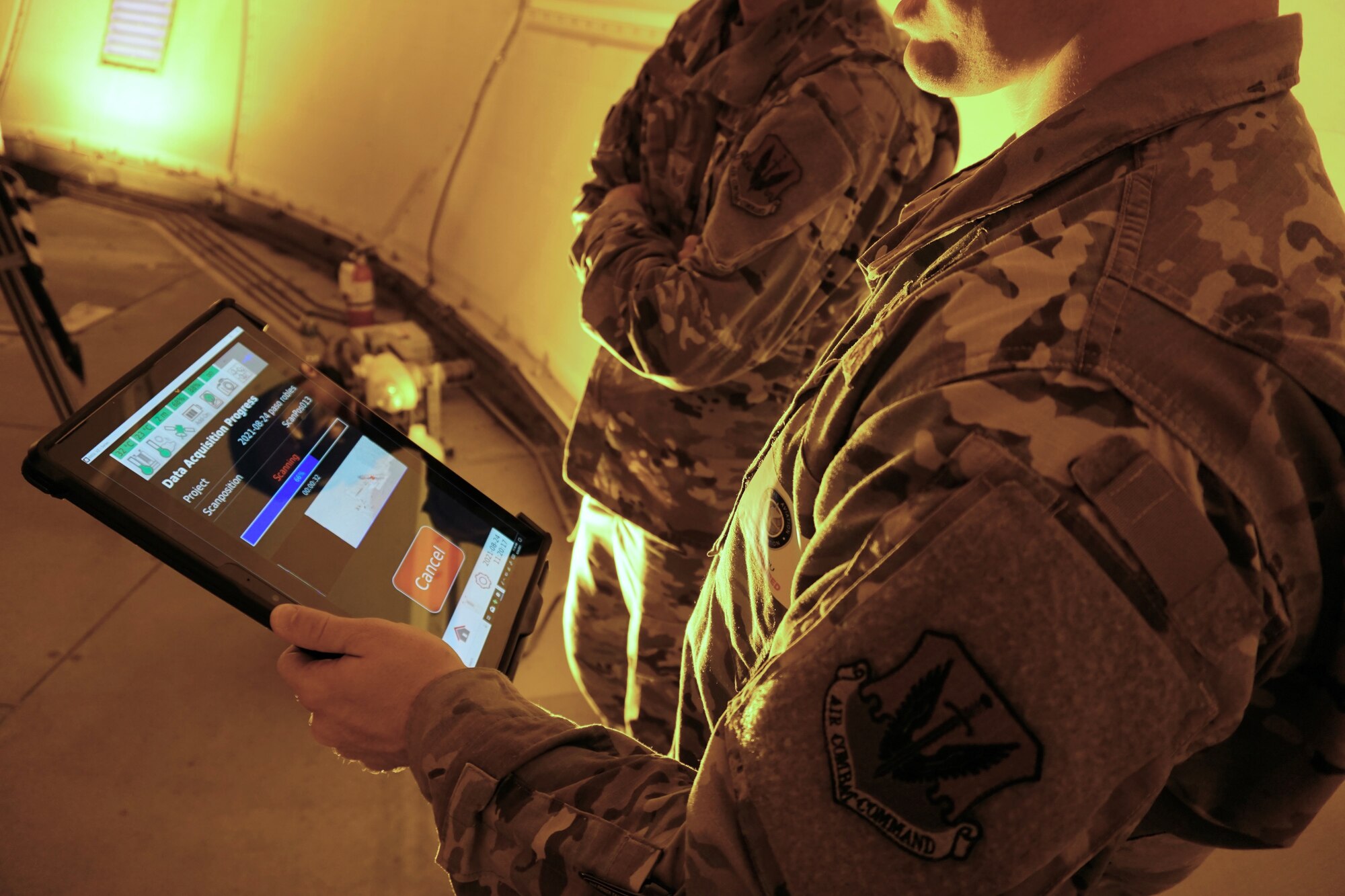 Photo of two U.S. Airmen one holding an electronic device