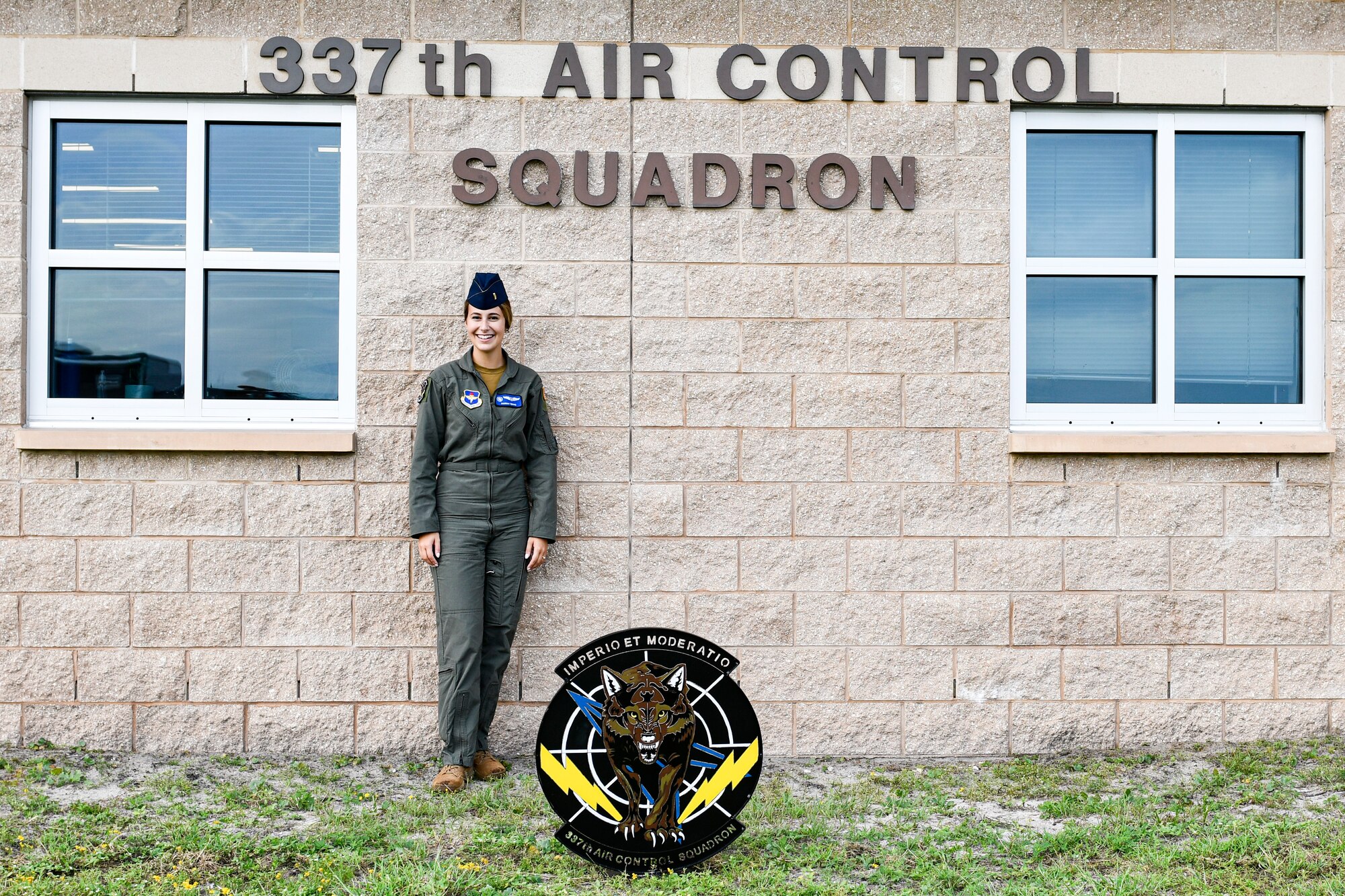 woman in flight suit standing in front of brick building