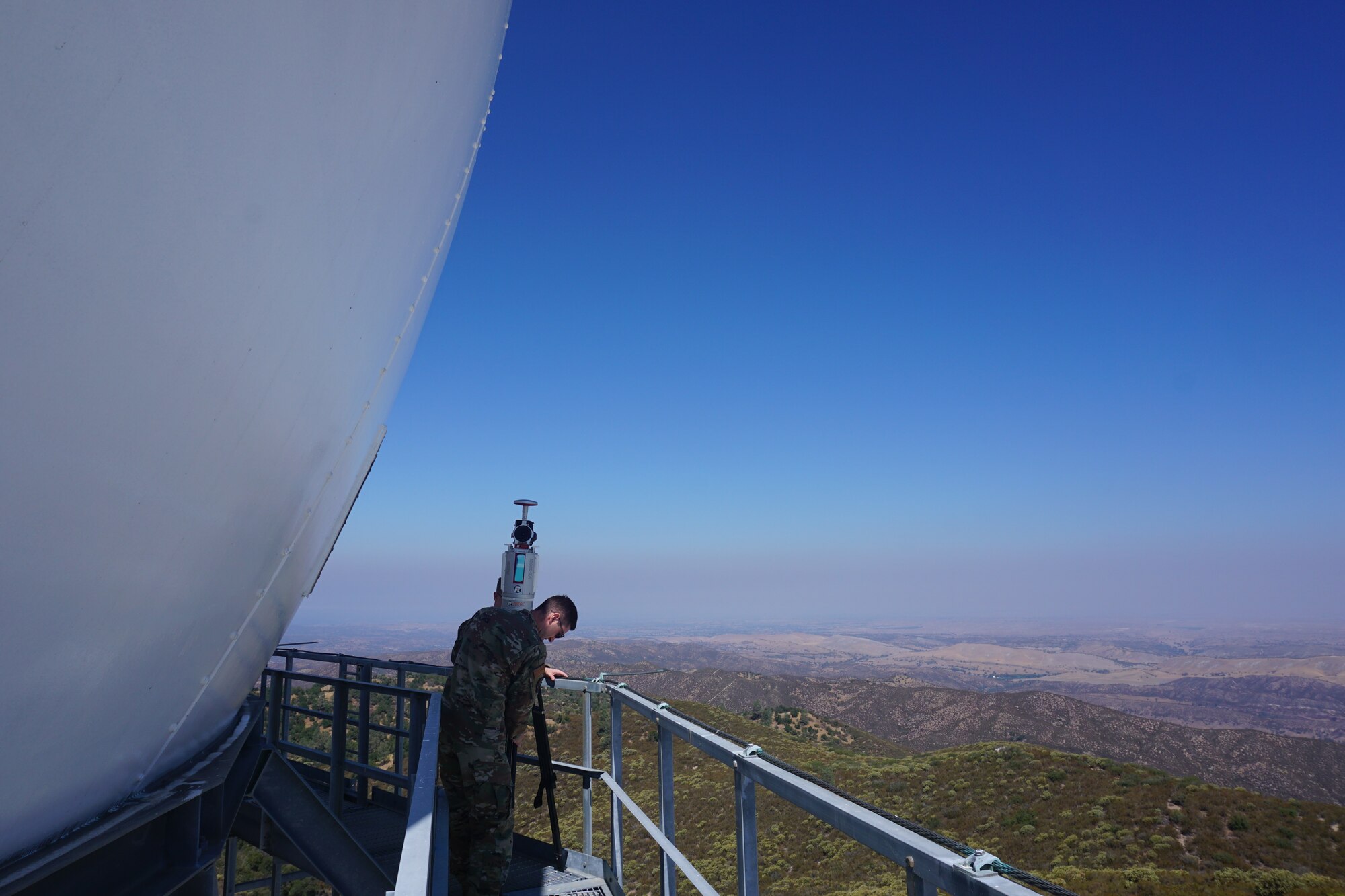 Two U.S. Airmen standing on railing around radar