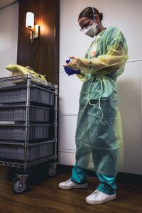 U.S. Navy Lt. Natashja Mortam, a nurse assigned to the Navy Medicine Readiness and Training Command, or NMRTC, from Twentynine Palms, California, dons her personal protective equipment.