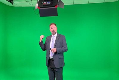 Man standing in front of green screen talking.