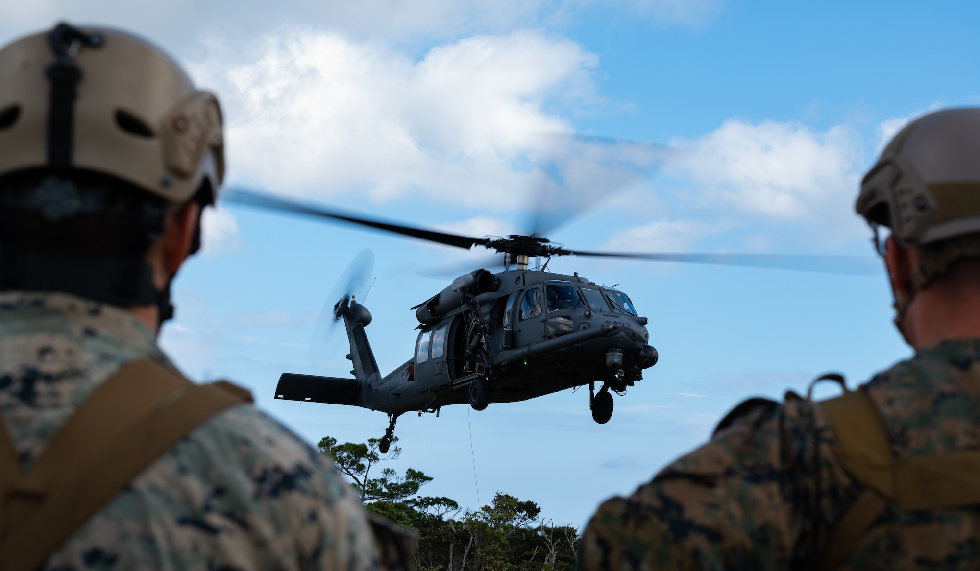 U.S. Marines from the 3rd Reconnaissance Battalion observe A 33rd Rescue Squadron HH-60 Pavehawk helicopter hovering at Camp Gonsalves, Japan, Sept.23, 2021. The 33rd RQS provides combat search and rescue capabilities to aid in exercises and real-world operations in the U.S. Indo-Pacific Command area of responsibility. (U.S. Air Force photo by Airman 1st Class Stephen Pulter)
