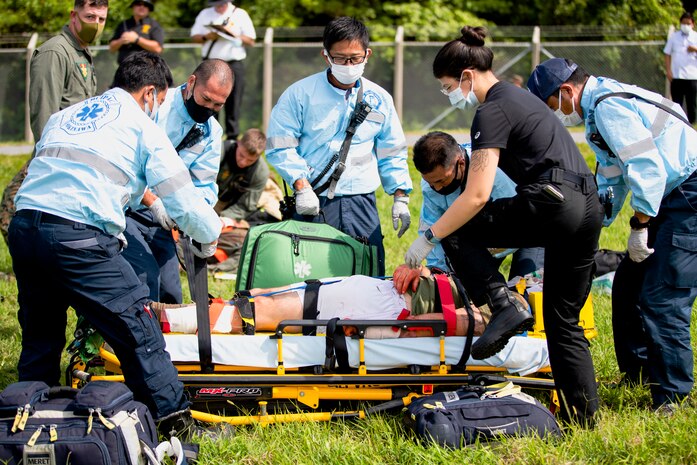 Master labor contractors with the Marine Corps Installations Pacific Fire Emergency Services load a patient onto a stretcher during an aircraft mishap drill near Gate 3 of Marine Corps Air Station (MCAS) Futenma, Okinawa, Japan, Sept. 21, 2021. The scenario was the signature event of Constant Vigilance 2021 on the air station and served to ensure MCAS Futenma and its personnel are able to respond to crises at a moment's notice. (U.S. Marine Corps photo by Cpl. Ryan H. Pulliam)