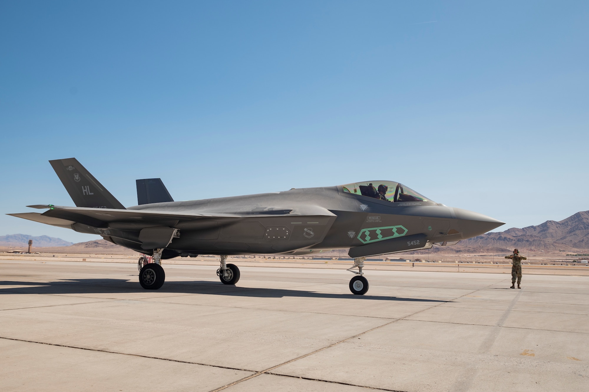 Airman 1st Class Javier Farcia-Bustos marshals an F-35A Lightning II as it taxis to complete the final test exercise of the nuclear design certification process at Nellis Air Force Base, Nevada, Sept. 21, 2021. This event included the first release of the most representative B61-12 test asset from an operationally representative F-35A, resulting in the B61-12 becoming the first F-35 weapon to complete development and intrgration during the aircraft’s modernization phase. (U.S. Air Force photo by Airman 1st Class Zachary Rufus)