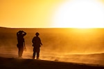Soldiers look at the sun on the horizon.