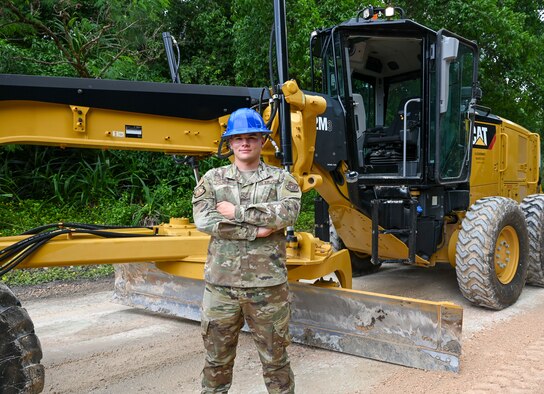 U.S. Air Force Senior Airman Cody Chenowith, pavements and equipment journeyman assigned to the 36th Civil Engineer Squadron, poses for a photo in front of a CAT 12M3 Grader, at Andersen Air Force Base, Guam, Aug. 25, 2021. Pavements and equipment airmen play a vital role in caring for the infrastructure on Andersen AFB. Chenowith spends his days balancing his duties at the 36th CES, base Honor Guard and re-launching the Guam Civil Air Patrol chapter, where he leads his team as the Andersen Flight Commander. (U.S. Air Force photo by Tech. Sgt. Esteban Esquivel)