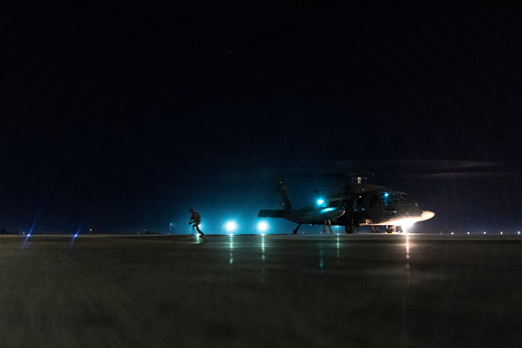 A military working dog handler disembarks a helicopter during a joint K-9 helicopter training mission