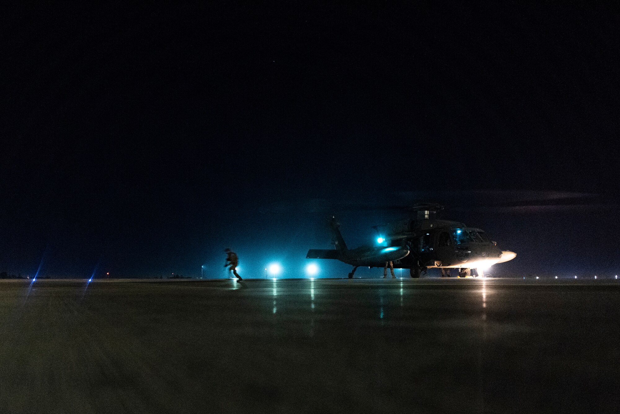 A military working dog handler disembarks a helicopter during a joint K-9 helicopter training mission